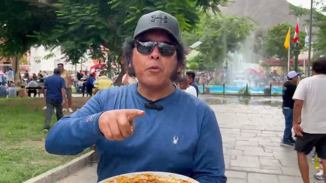 Pedro González Toledo reporta en una feria gastronómica en la plaza de un pueblo, con la pileta y el público detrás